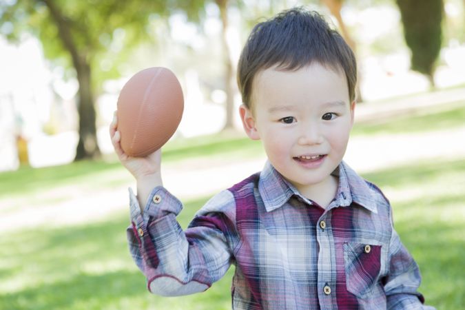 Cute Young Boy Playing Football Outside