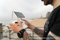 Sideview of man with remote for drone on wooden boardwalk on beach 42PP10