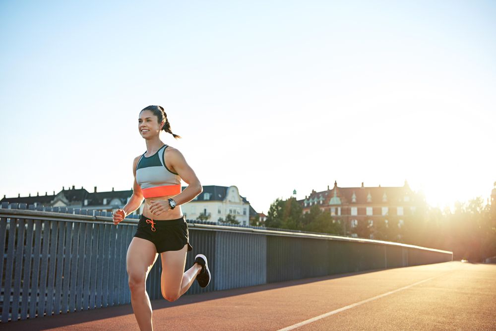 Smiling healthy athlete on her morning jog across bridge