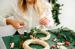 Woman decorating Christmas wreath at home