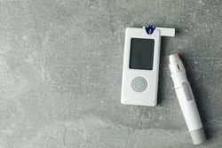 Blood glucose meter on gray background, space for text