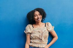 Portrait of Black Latina woman smiling in front of wall