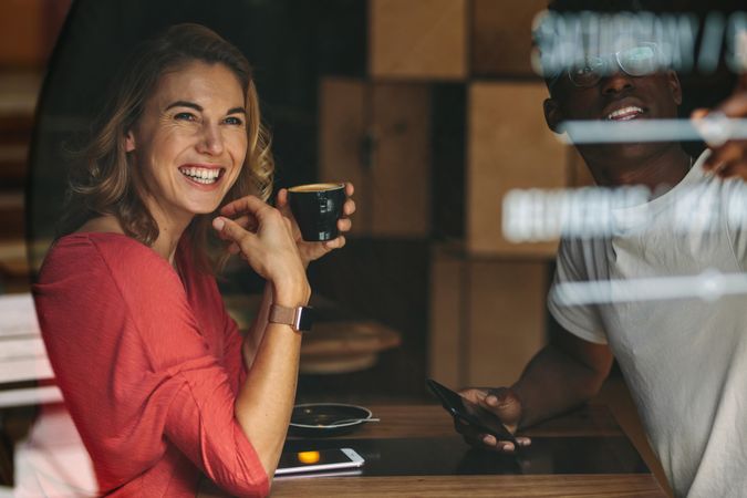 Smiling woman sitting at a coffee table holding a coffee cup