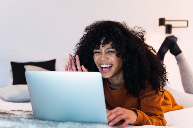 Excited Black woman browsing laptop at home