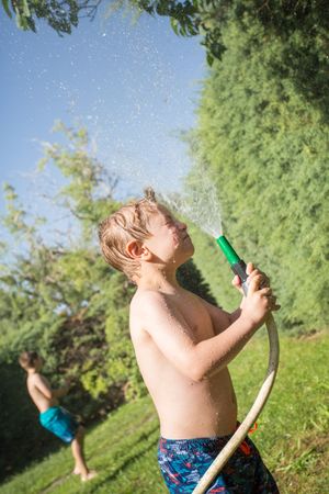 Little kids in swimwear having fun with splashing water