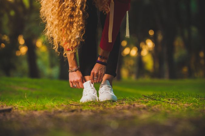Sportive curly woman bending forward on lawn