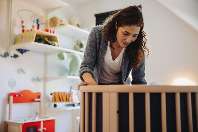 Woman putting her baby to sleep in crib