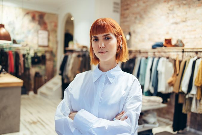 Portrait of a confident young woman standing with her arms crossed in her clothing store