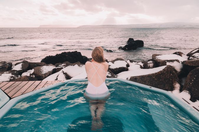 Woman sitting in pool near stones