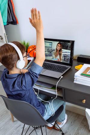 Teenager with headphones receiving class at home with laptop from his bedroom