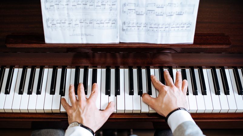 Crop male hands playing piano