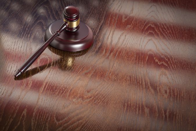 Wooden Gavel Resting on Flag Reflecting Table