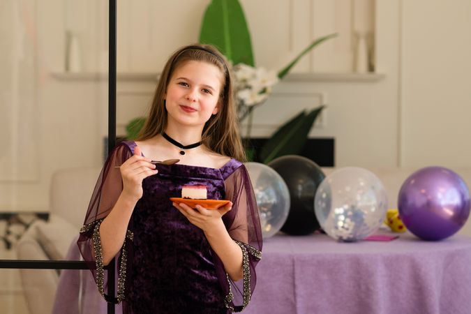 Girl holding plate with cake and smiling at birthday party.