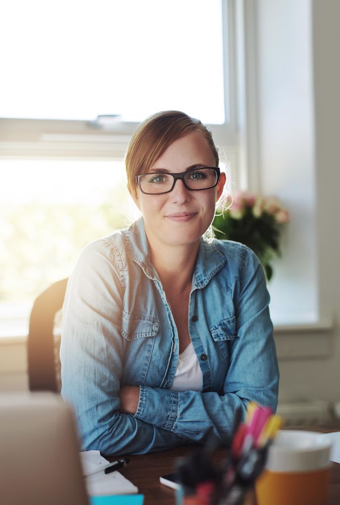 Confident female entrepreneur sitting at her desk in her bright home office, vertical