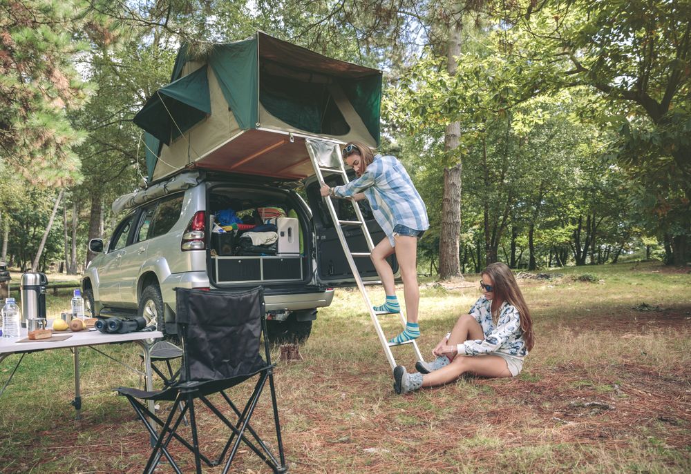 Woman climbing ladder to tent over car