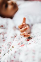 Close up of baby boy’s hands with boy’s face in the background