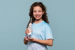 Smiling girl holding an electric toothbrush