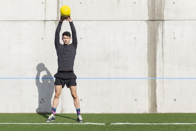 Man training with kettlebell on lawn