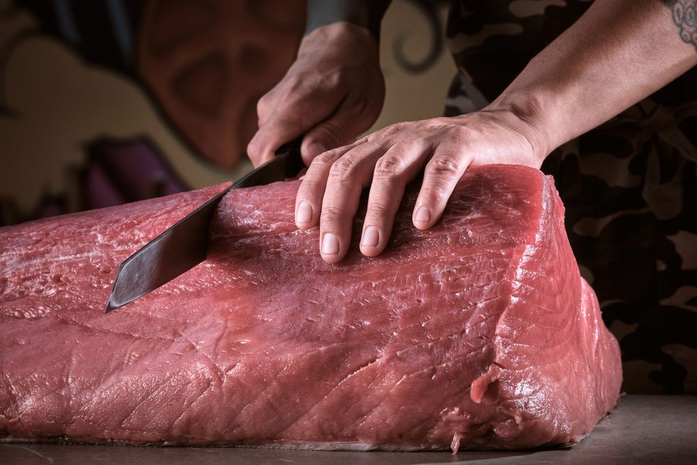 Male hands of a chef cutting a delicious loin of fresh bluefin t