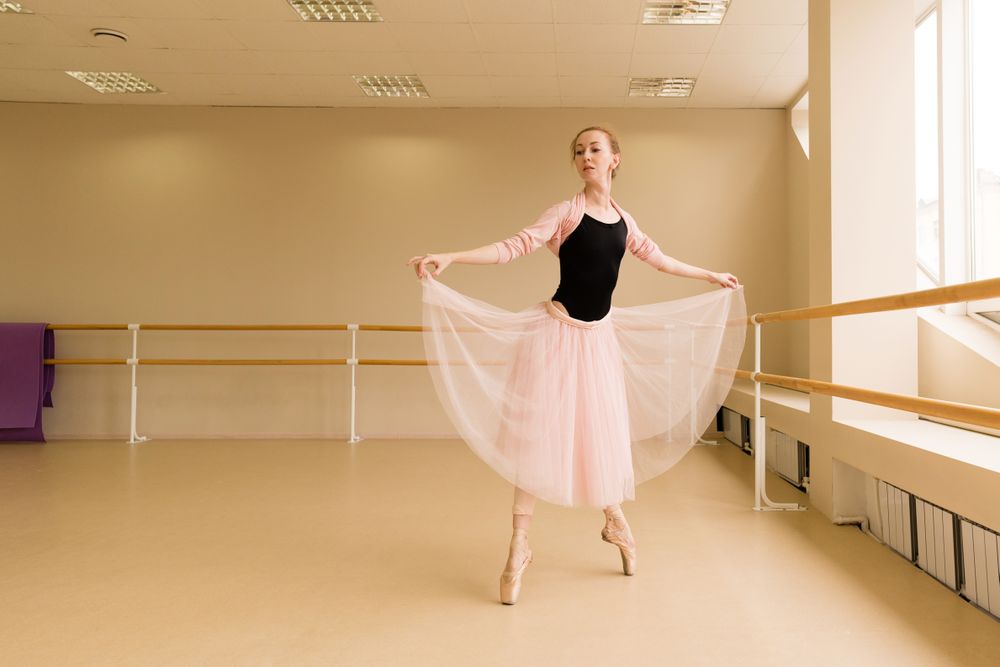 Ballet dancer lifting tutu skirt, standing en pointe