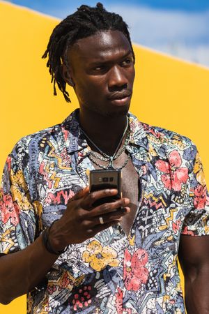 Stylish Black man in colorful shirt with smartphone