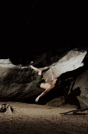 Man practicing rock climbing among large rocks in a forest