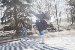 Guy looking at man dancing break dance in park