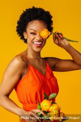 Smiling Black woman playing with ranunculus flowers 4AnZ6b