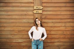 Woman leaning on wooden wall with two signs