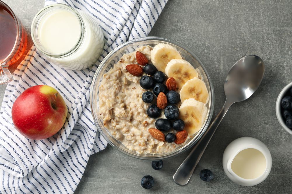 Composition with oatmeal porridge with fruits on gray background