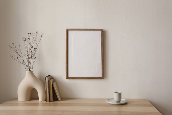 Table with modernist vase and decorative reeds, coffee and blank frame