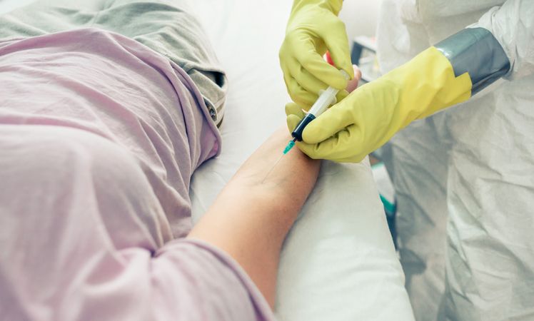 Doctor taking blood sample from patient lying on the gurney
