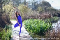 Female wearing purple sport clothes and doing yoga pose on one leg 4BZv34
