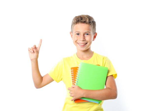 Boy in yellow t-shirt with copybooks isolated on blank background