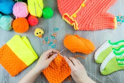 Woman knitting orange piece of clothing
