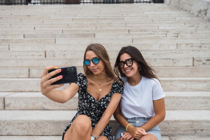 Laughing women taking selfie on stairs at old building