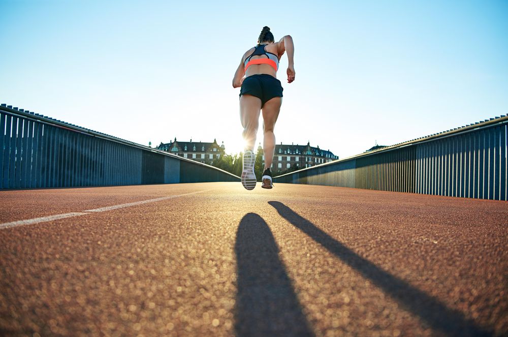Shot of fit woman’s running away from camera on bridge