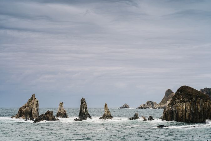 Rocky peaks protrude from water in cloudy day