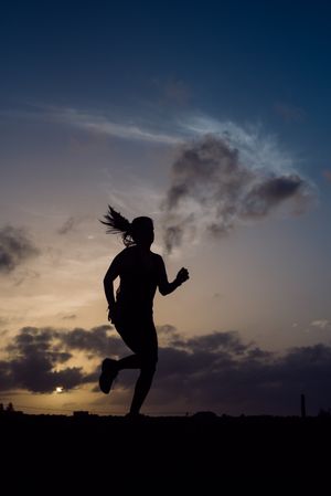 Jumping woman and sky with clouds at sunset