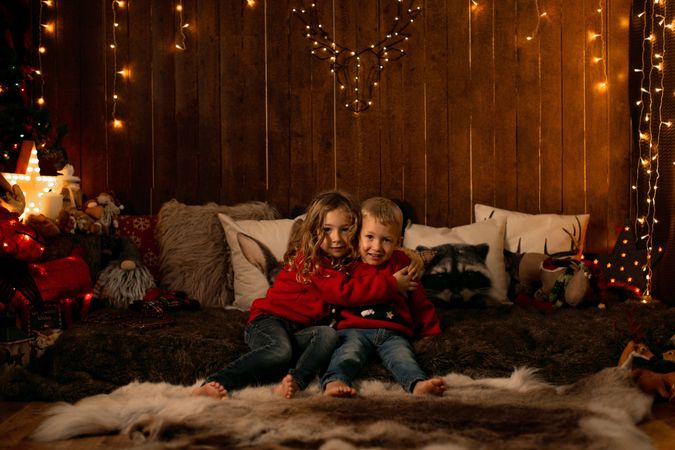 Siblings sitting in a room with christmas decoration