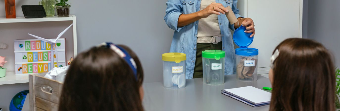 Unrecognizable teacher teaching how to recycle by sorting waste