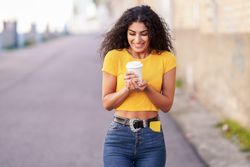 Female in yellow t-shirt walking on street with coffee