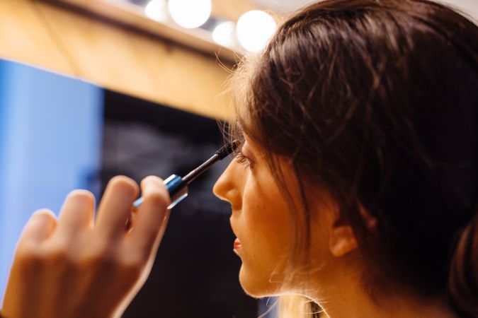 Young female applying mascara in front of mirror