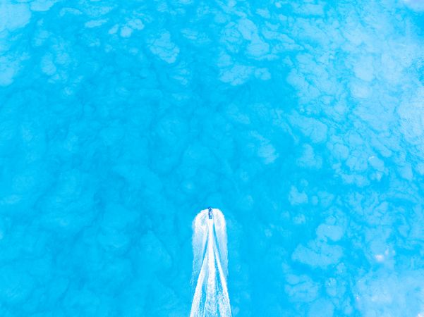Top down view of a jet ski traveling over a blue water.