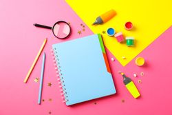 Flat lay composition with school supplies on two tone background, space for text