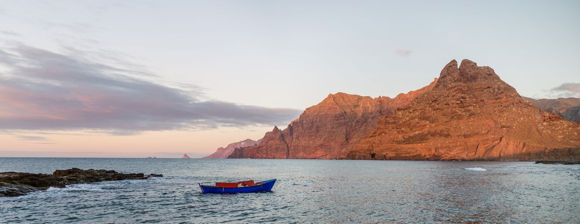 Blue sailboat in sea and beautiful rocks