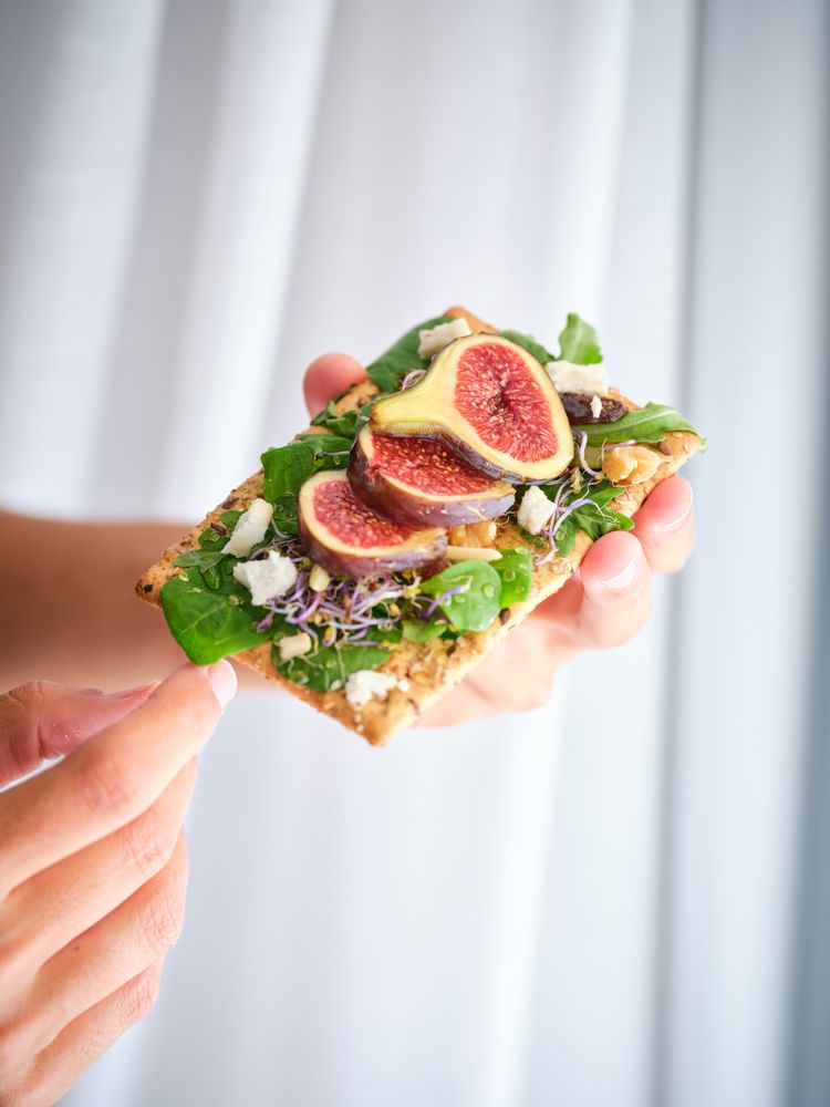 Crop person with delicious fruit slices on bread