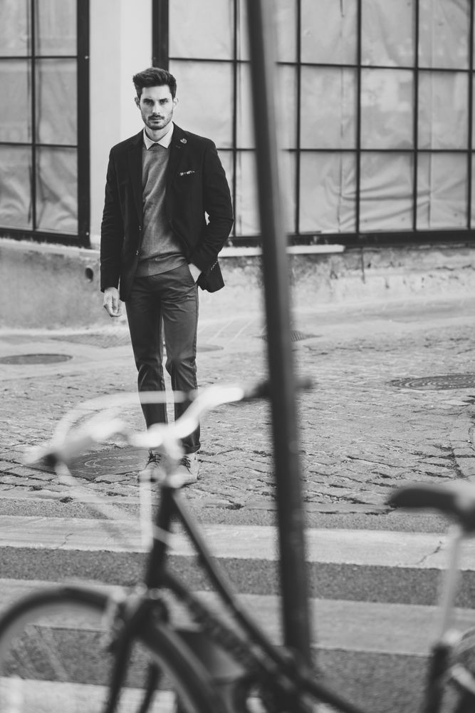 Moody shot of man in the street wearing elegant suit with vintage bicycle in foreground, b&w