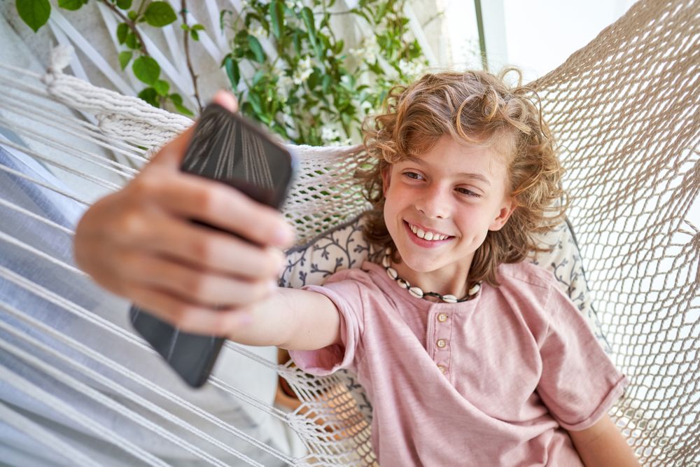 Positive boy taking selfie in hammock