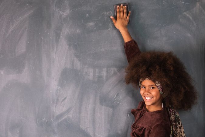 Black girl writing on chalkboard in classroom